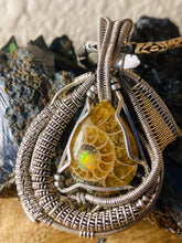 Load image into Gallery viewer, Faceted Ethiopian Opal set into an ammonite fossil cabochon wire wrapped in sterling .925
