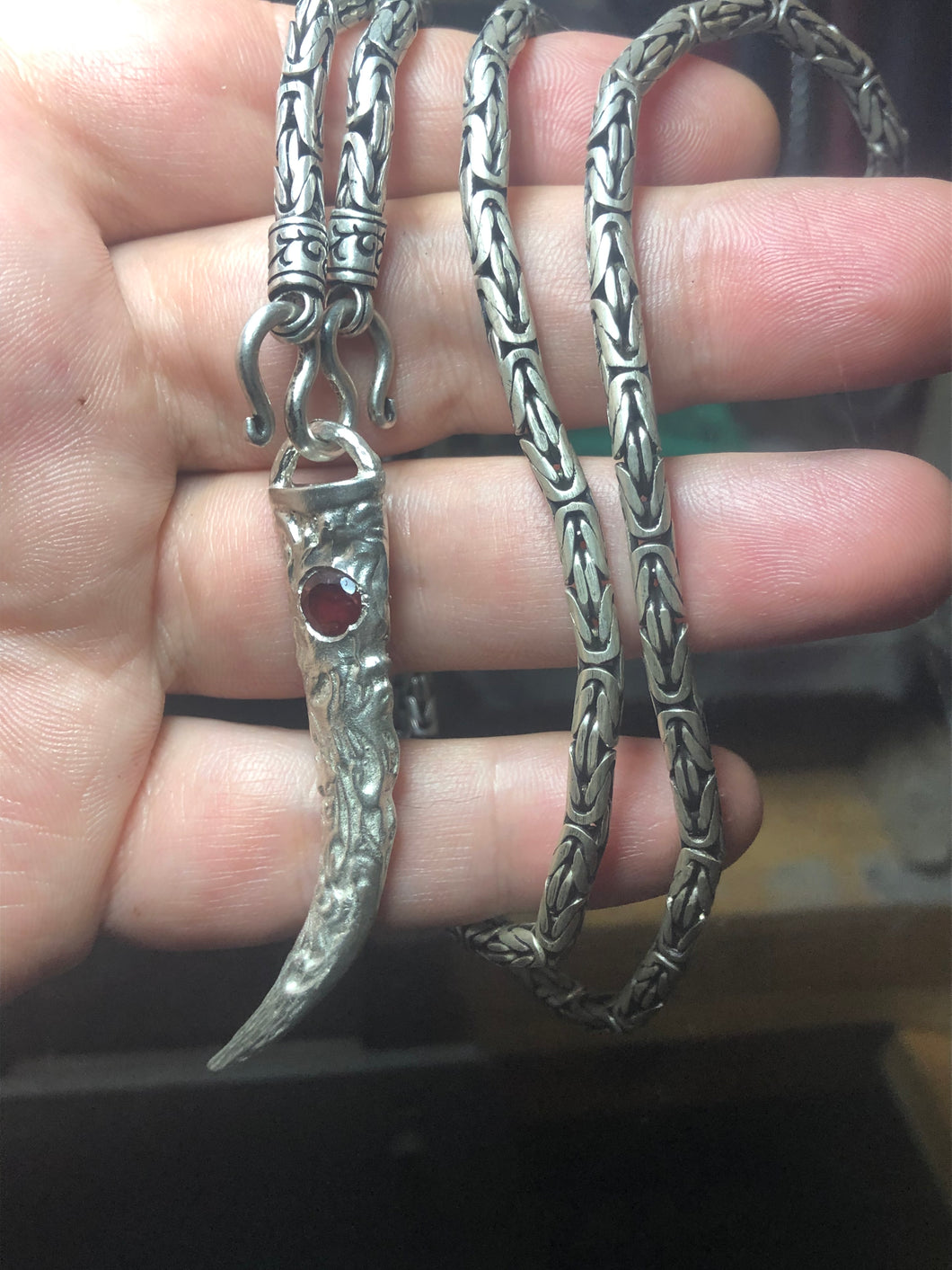 Scrollwork wolf tooth pendant with cast in place garnet setting on Thai Byzantine chain.